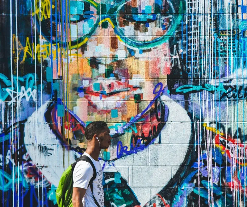 student walking past a colorful mural of a child's head