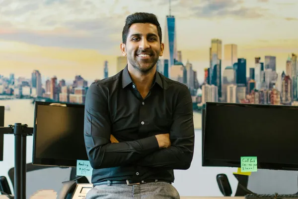 Stock portrait of young male sitting amongst laptops